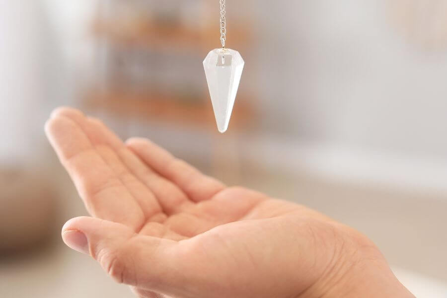BLOG POSTS 600 x 900 (5) A psychic reader's hand lay out flat, palm facing upwards whilst swinging a pendulum