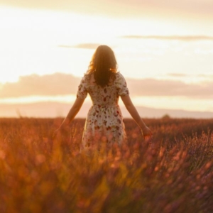Clairsentient-image1 A woman in a white dress with her arms out by her side in a wheat field whilst the sunsets