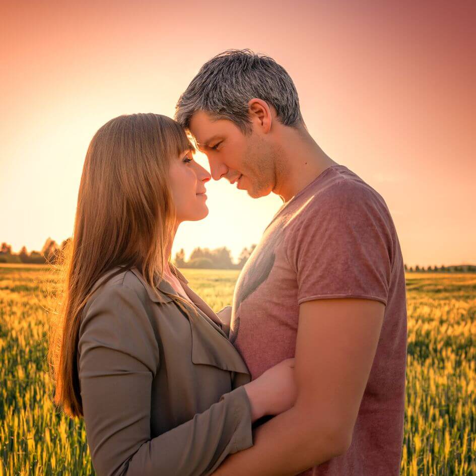 Couples A man and a woman looking at each other touching noses in the sunset